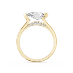 A pear cut diamond sits sideways across this yellow gold engagement ring, secured by an asymmetrical partial bezel setting