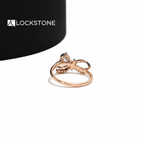 A pear shaped lab diamond sits between curved rose gold ribbon bands accented with small round pavé diamonds
