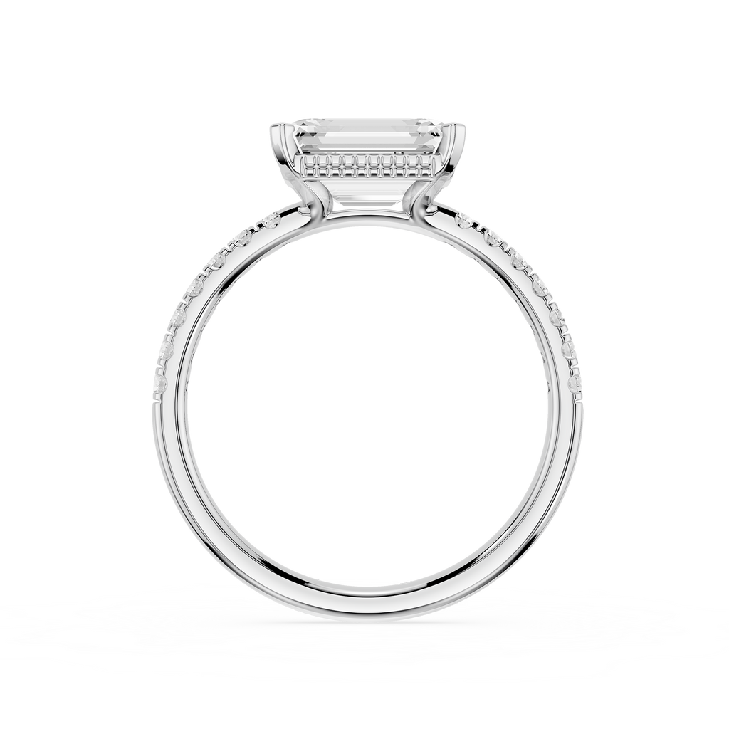 A silver-toned engagement ring featuring a rectangular baguette-cut center stone in a prong setting, with a micro-beaded halo and a pavé-set shank, shown on a solid white background.