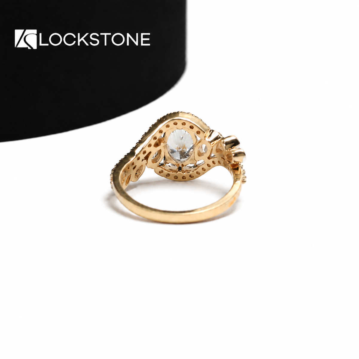 A prong set oval diamond sits between graduated side diamonds on this yellow gold ring with sweeping diamond accented curves