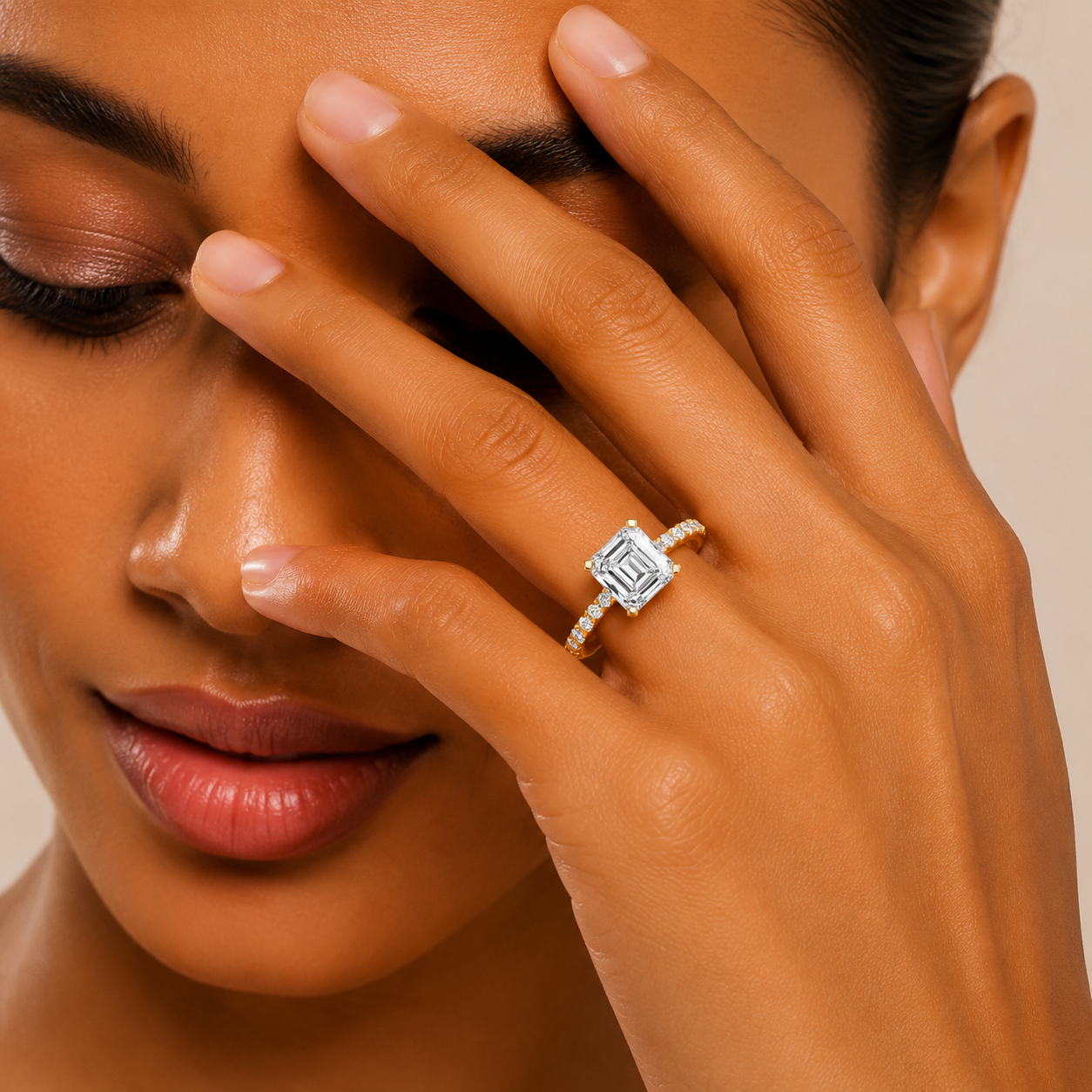 A close-up lifestyle shot of a woman wearing a silver ring with a square-cut clear gemstone on her finger, with her hand resting against her face.