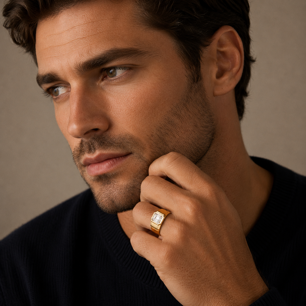 Man wearing a gold ring with a diamond, looking to the side against a neutral background