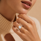 Close-up of a hand wearing a diamond ring with a neutral background