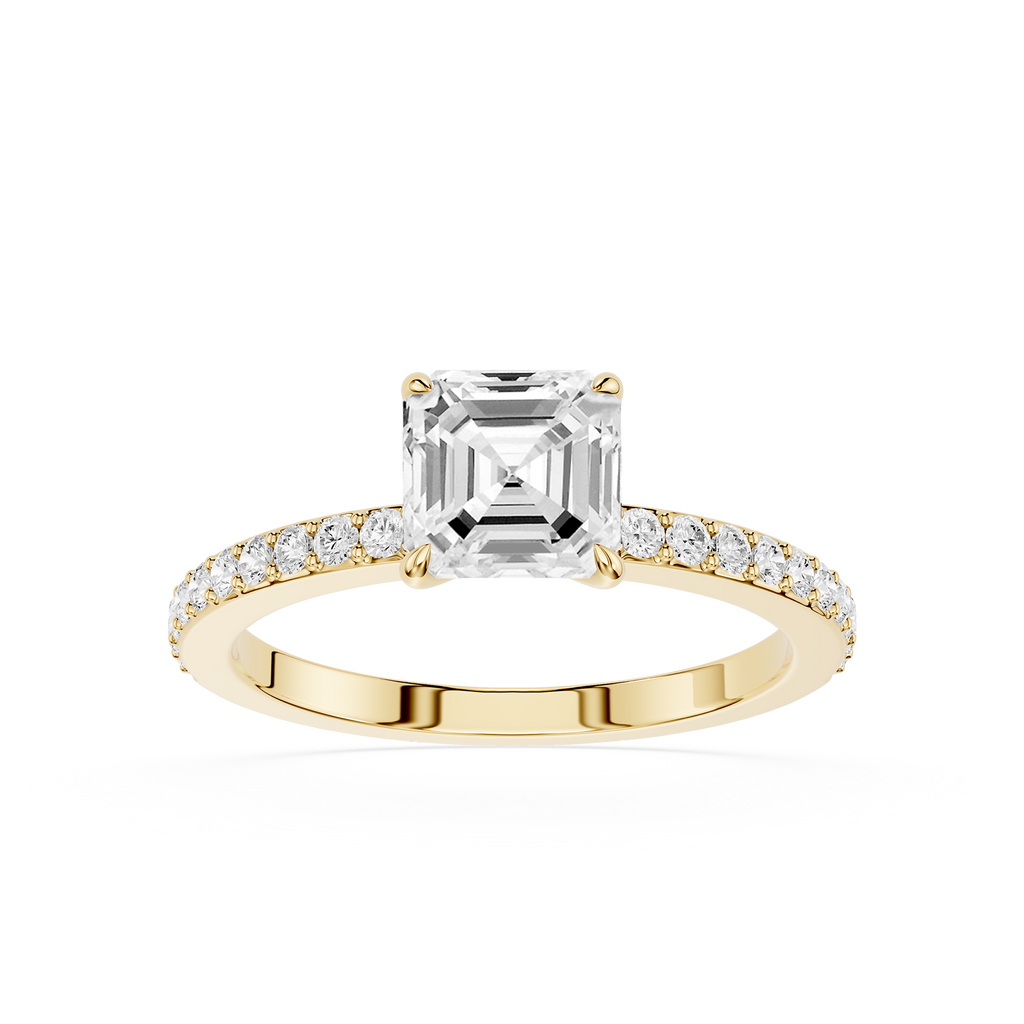 An emerald-cut diamond engagement ring in a Yellow-colored metal setting, featuring a pave band with small round diamonds, shot against a solid white background.