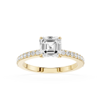 An emerald-cut diamond engagement ring in a Yellow-colored metal setting, featuring a pave band with small round diamonds, shot against a solid white background.