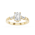 Gold ring with emerald-cut diamond and baguette side stones on a white background