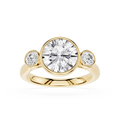 Gold ring with a large central diamond and two smaller diamonds on either side against a white background