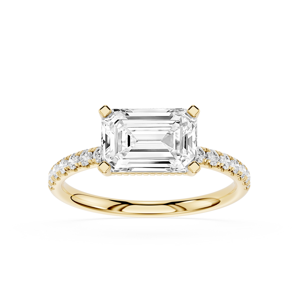 An emerald-cut diamond engagement ring in yellow gold with pavé-set diamonds on the band, shown on a clean white background.