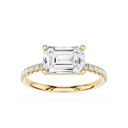 An emerald-cut diamond engagement ring in yellow gold with pavé-set diamonds on the band, shown on a clean white background.