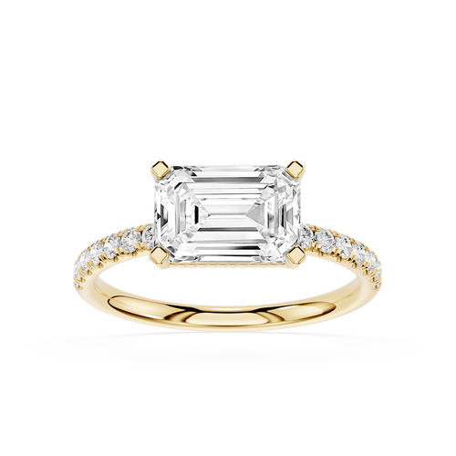 An emerald-cut diamond engagement ring in yellow gold with pavé-set diamonds on the band, shown on a clean white background.
