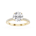 A yellow gold engagement ring featuring a round brilliant-cut diamond center stone and a pavé-set diamond band, shown on a clean white background.