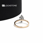 Elongated marquise cut diamond engagement ring with a raised center stone and round brilliant diamond lined shank