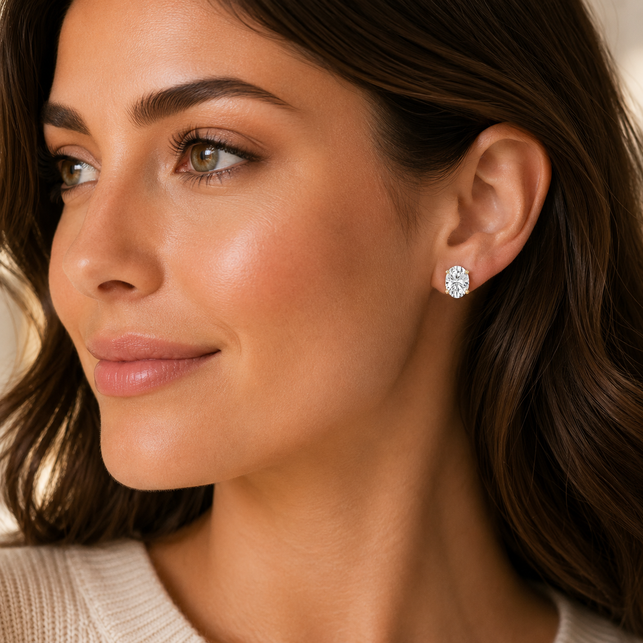 Close-up of a woman wearing a diamond earring with a neutral background