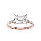 An emerald-cut diamond ring in rose gold with a pavé band, shown on a clean white background.