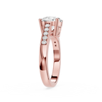 A rose gold engagement ring featuring a round brilliant-cut center stone and a pavé row of small round stones on the shank, shown on a clean white background.