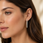 Close-up of a woman wearing diamond hoop earrings with a neutral background