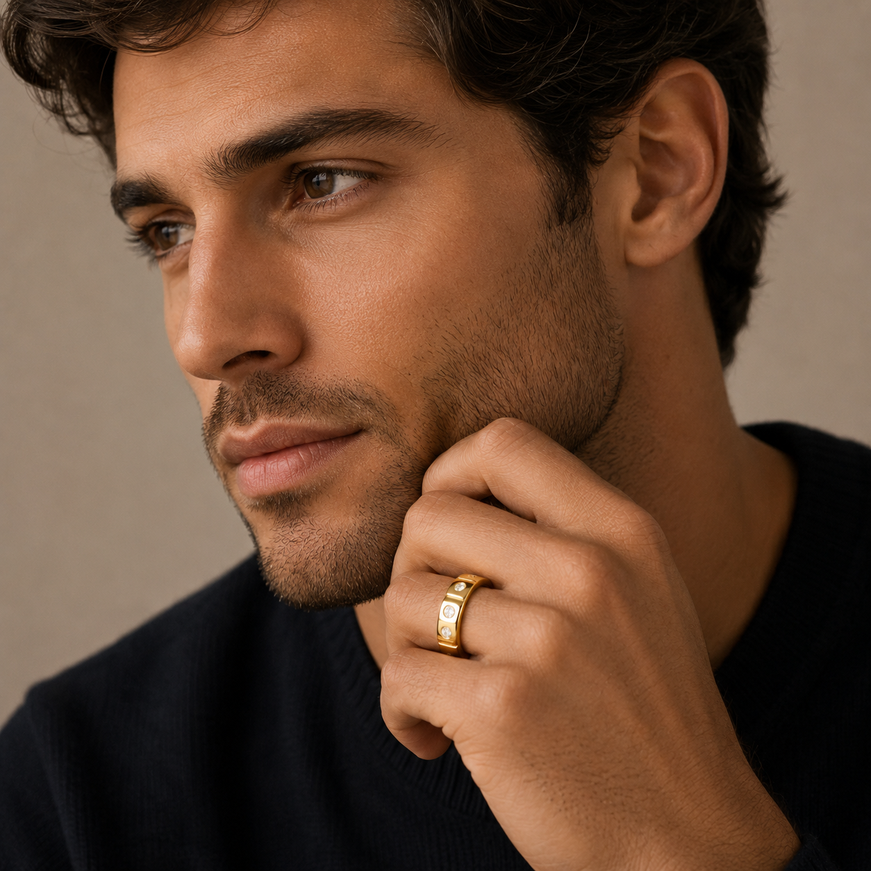 Man wearing a gold ring on his finger against a neutral background