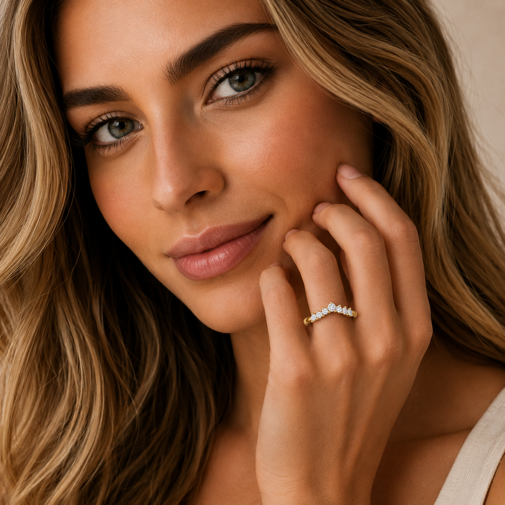 Close-up of a woman with a diamond ring on her finger, wearing a beige top.