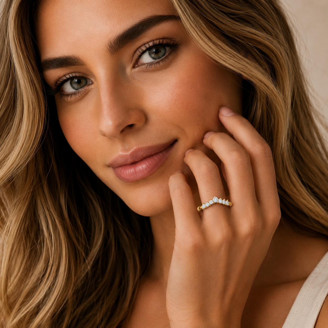 Close-up of a woman with a diamond ring on her finger, wearing a beige top.