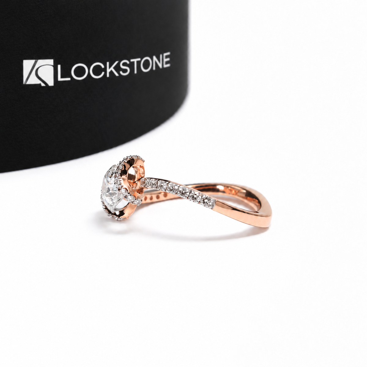 A round lab grown diamond sits between crossing pavé bands on this rose gold engagement ring with an open twist design