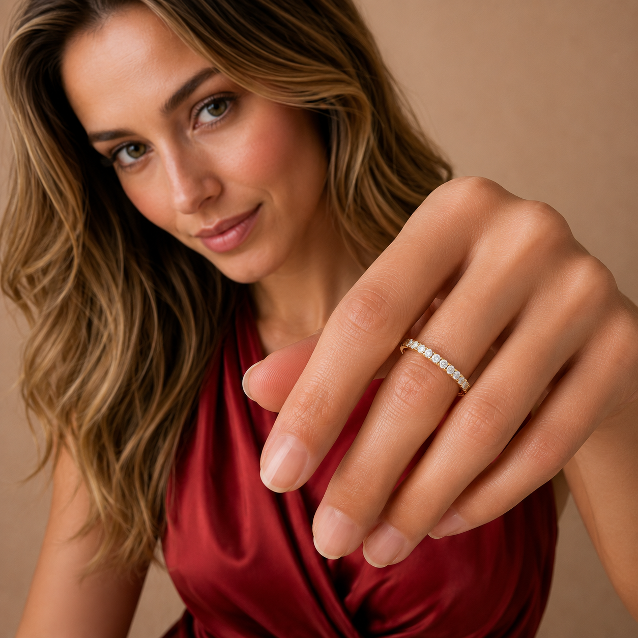 A close-up lifestyle shot of a woman wearing a delicate silver band ring set with small clear stones on her ring finger, against a warm beige background.