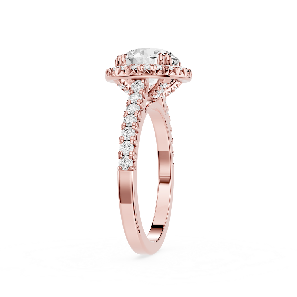 A rose gold engagement ring featuring a round-cut diamond center stone in a halo setting, with pave diamonds along the shank, shown on a plain white background.