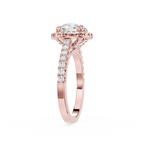 A rose gold engagement ring featuring a round-cut diamond center stone in a halo setting, with pave diamonds along the shank, shown on a plain white background.