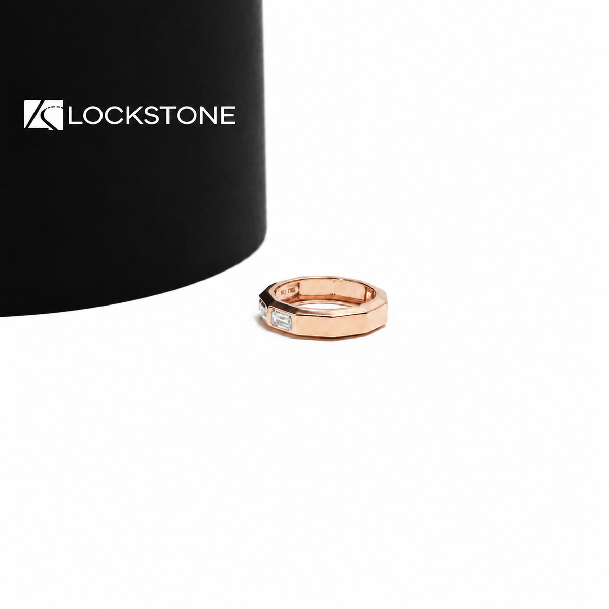 Three east west emerald cut diamonds sit across the front of this rose gold anniversary ring with a wide polished band