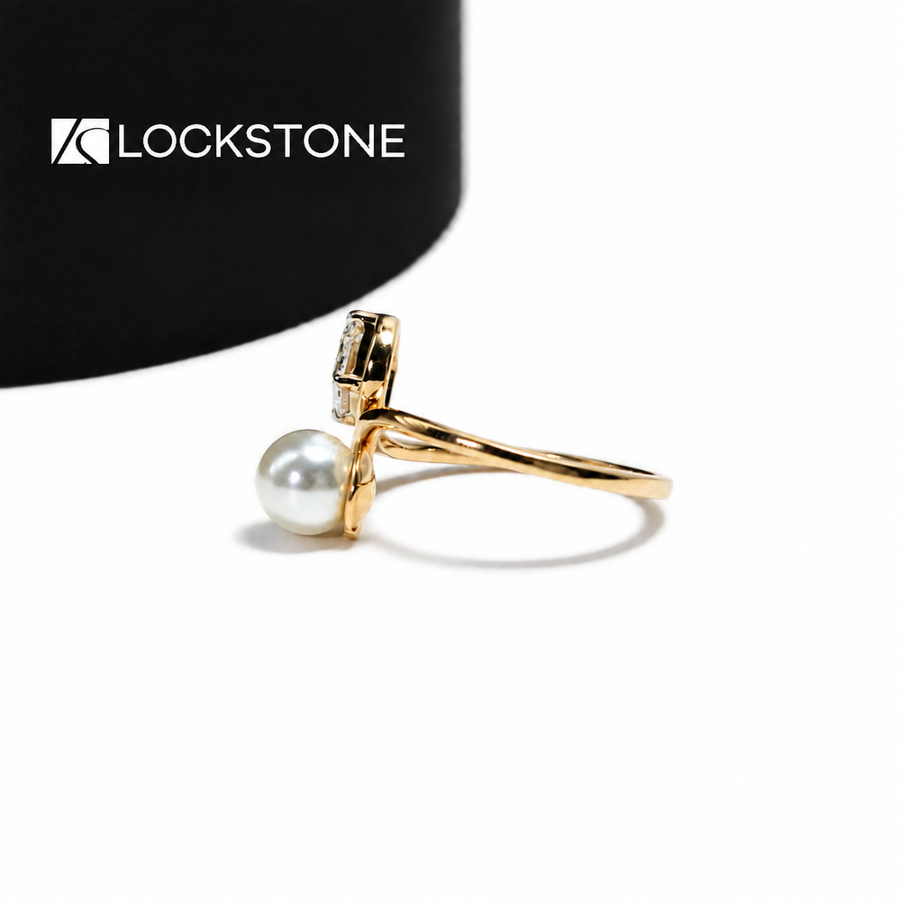 A rectangular emerald cut diamond pairs with a round white pearl on this yellow gold ring with sweeping curved shoulders