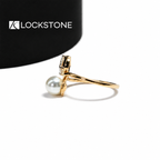 A rectangular emerald cut diamond pairs with a round white pearl on this yellow gold ring with sweeping curved shoulders