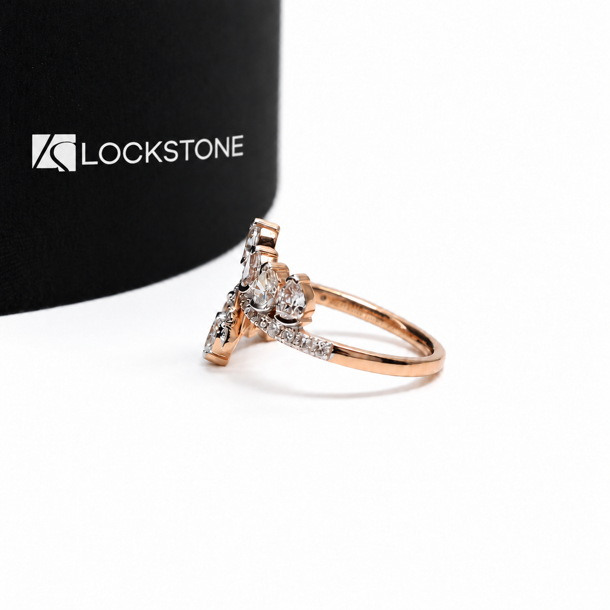 An open rose gold diamond statement ring with staggered oval and pear shaped stones along sweeping diamond studded arms