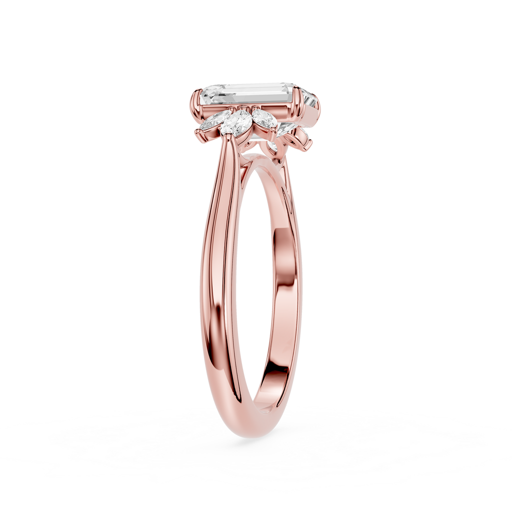 A rose gold engagement ring featuring an emerald-cut center stone and smaller marquise-cut side stones, shown on a clean white background.