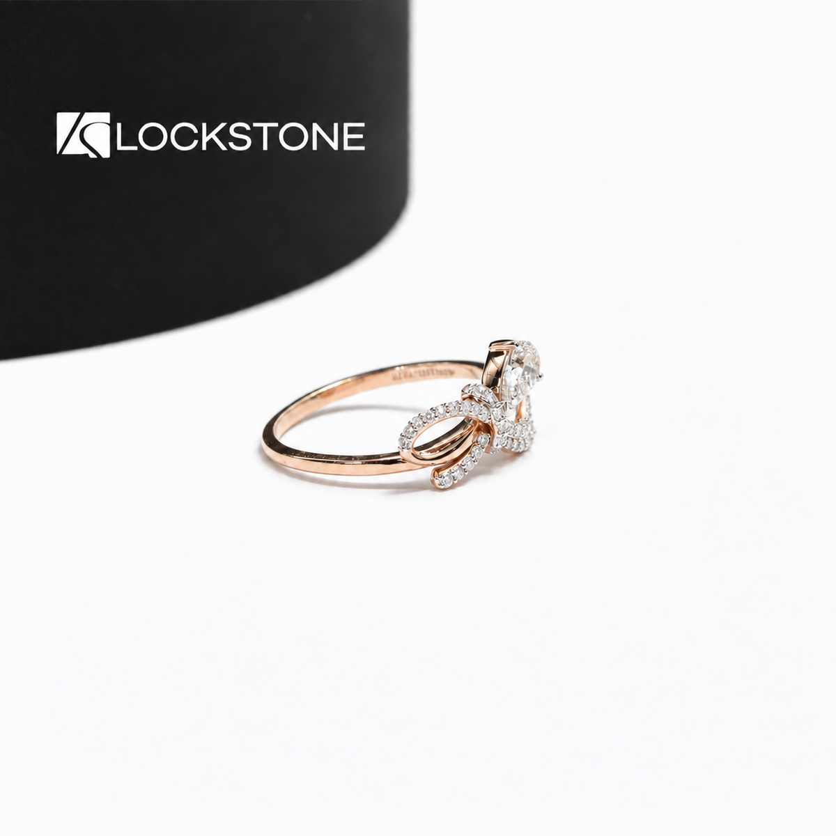 Pear diamond bow engagement ring in rose gold showcasing a prong set center stone and intertwined diamond lined shoulders
