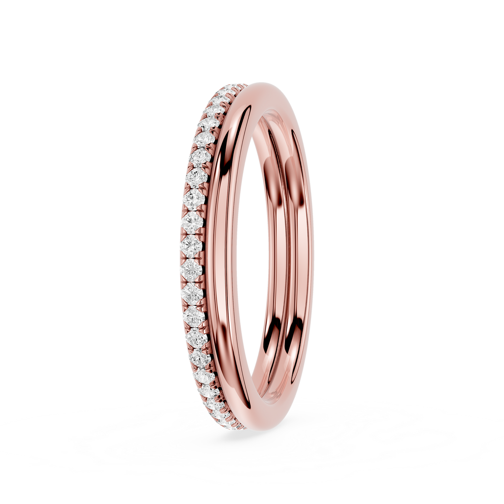 A rose gold eternity-style wedding band featuring a channel-set row of clear pavé diamonds on one side, shown on a clean white background.