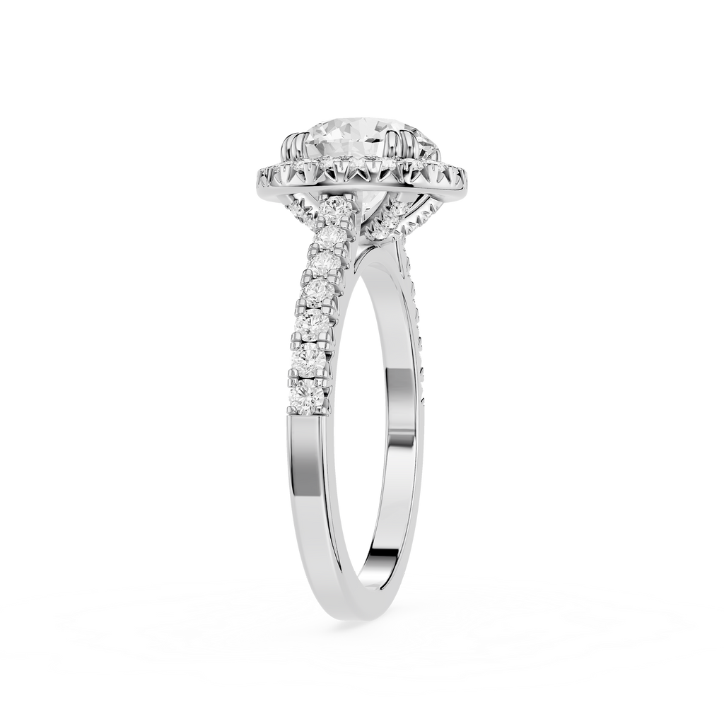 A silver-toned diamond engagement ring with a round-cut center stone, a halo of smaller diamonds, and a shank accented with pavé diamonds, shown on a clean white background.