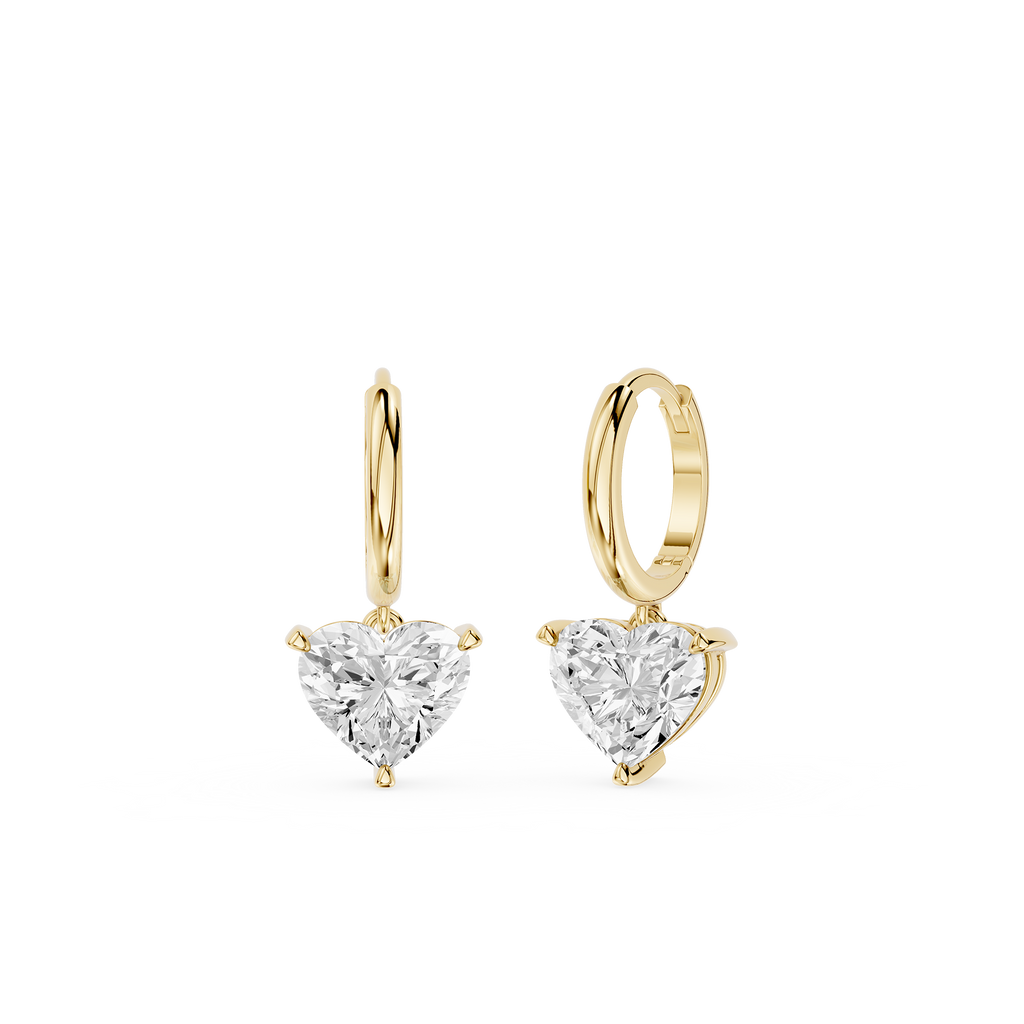 Gold hoop earrings with heart-shaped clear gemstones on a white background