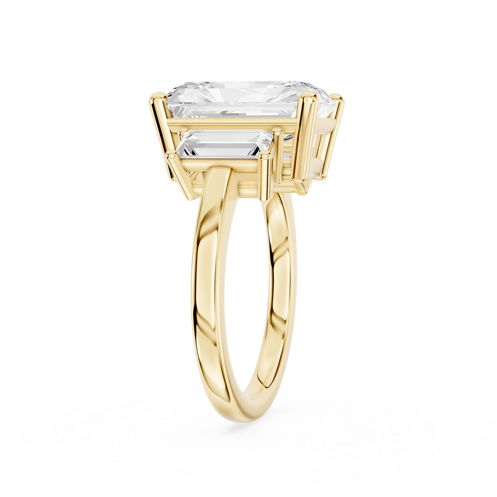 Rectangular radiant diamond three stone ring in yellow gold with two tapered baguette diamonds beside the center stone