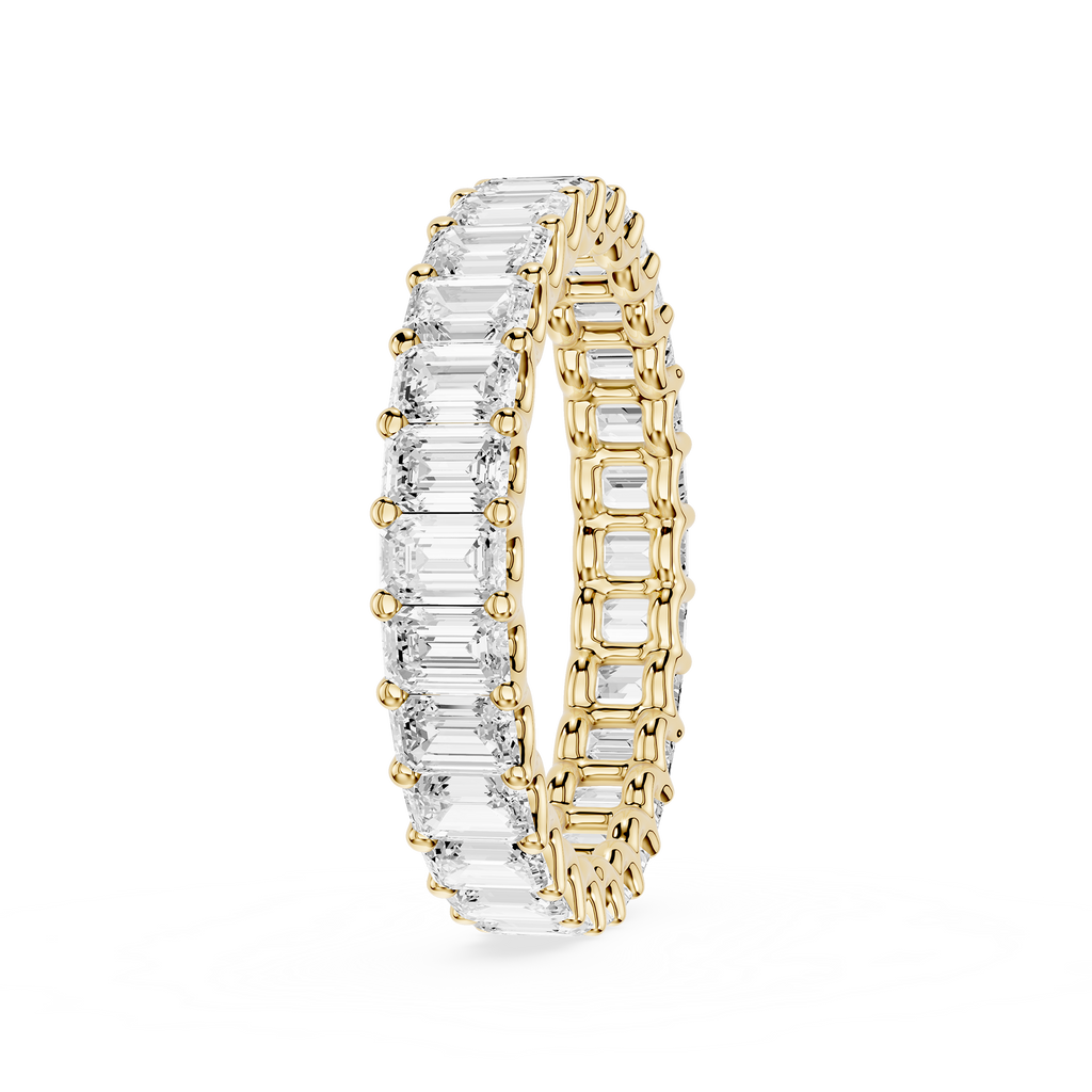 A yellow gold eternity ring featuring a continuous row of baguette-cut clear gemstones on one side and round-cut stones on the other, shown on a plain white background.