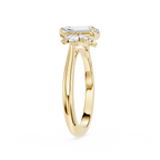 A yellow gold ring featuring a baguette-cut clear center stone and three marquise-cut side stones, shown on a plain white background.