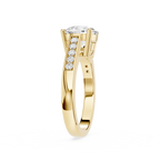A yellow gold ring featuring a round-cut diamond center stone and a pavé row of smaller round diamonds on the shank, shown against a plain white background.