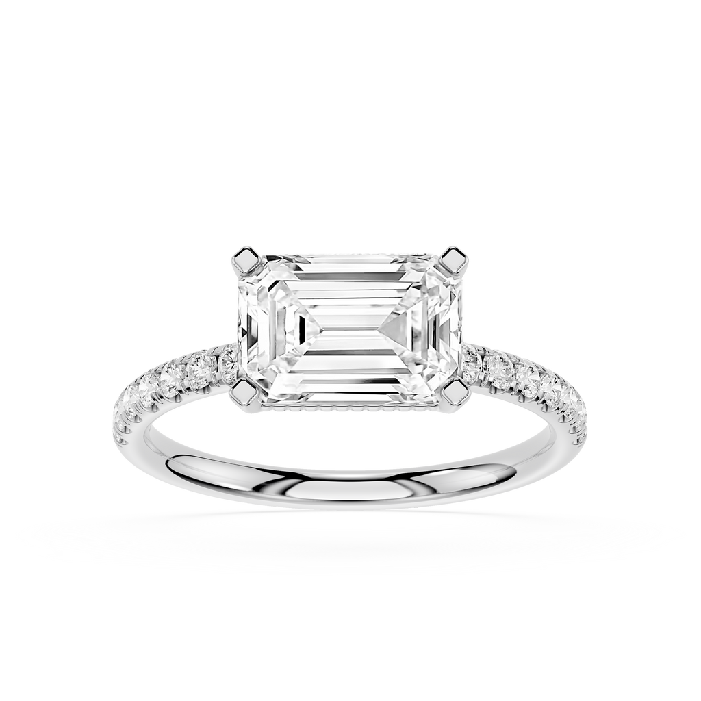 An emerald-cut diamond engagement ring in a silver-colored metal band with pavé-set accent diamonds, shown on a clean white background.