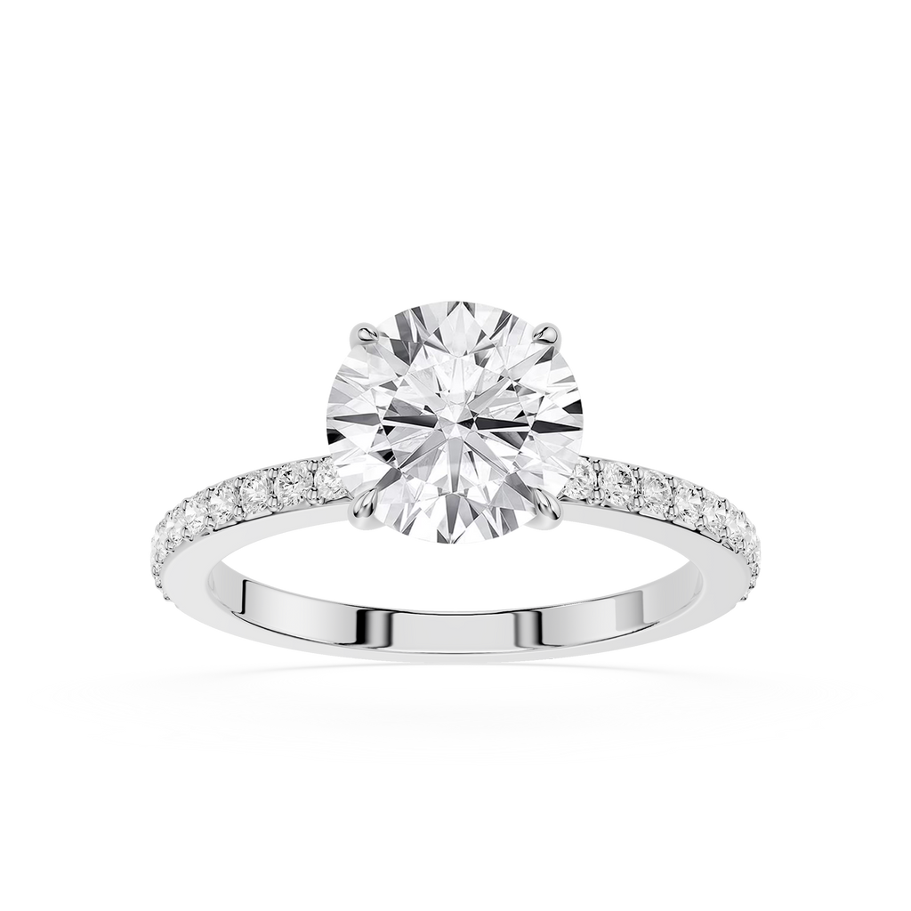 A round-cut diamond engagement ring with a brilliant solitaire center stone and a pavé-set diamond band in a silver-toned metal, shown on a plain white background.
